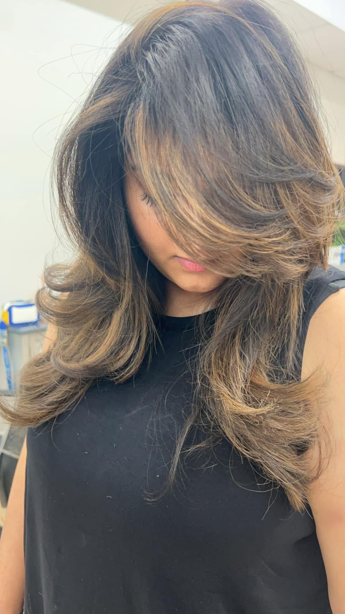 Voluminous layered blowout with caramel highlights and curled ends