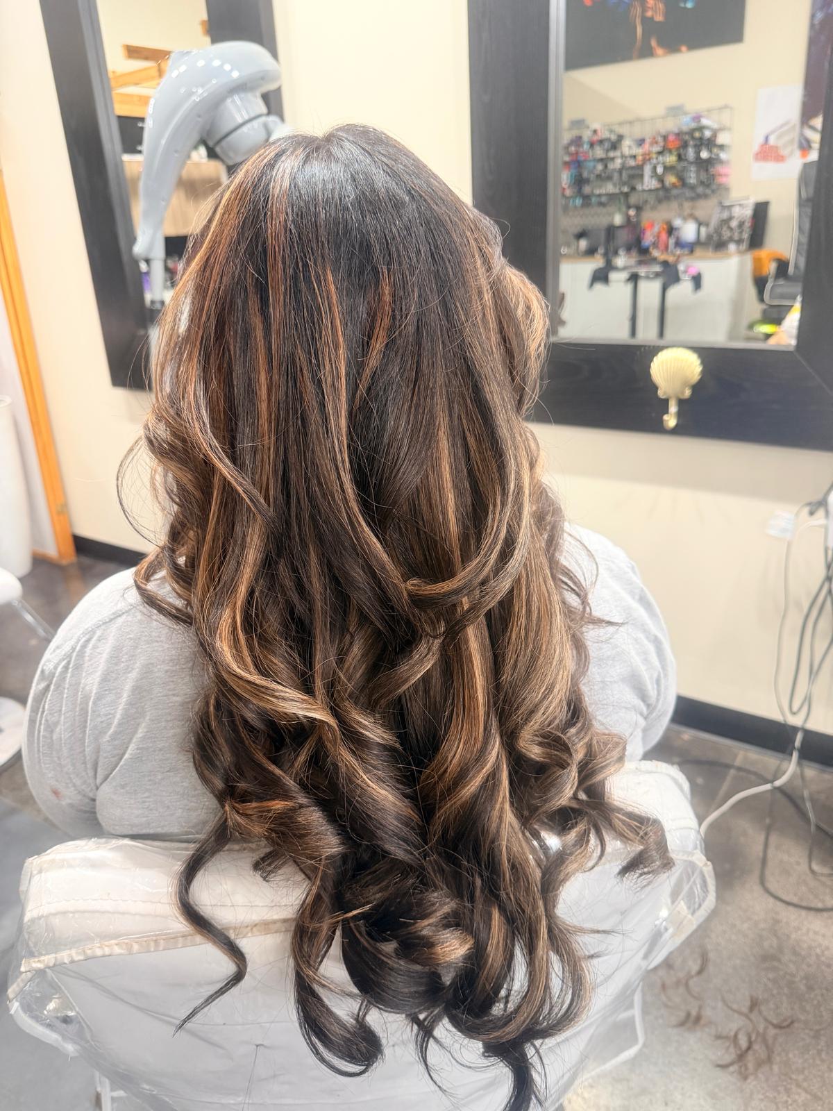 Long hair with warm copper highlights styled in large soft curls