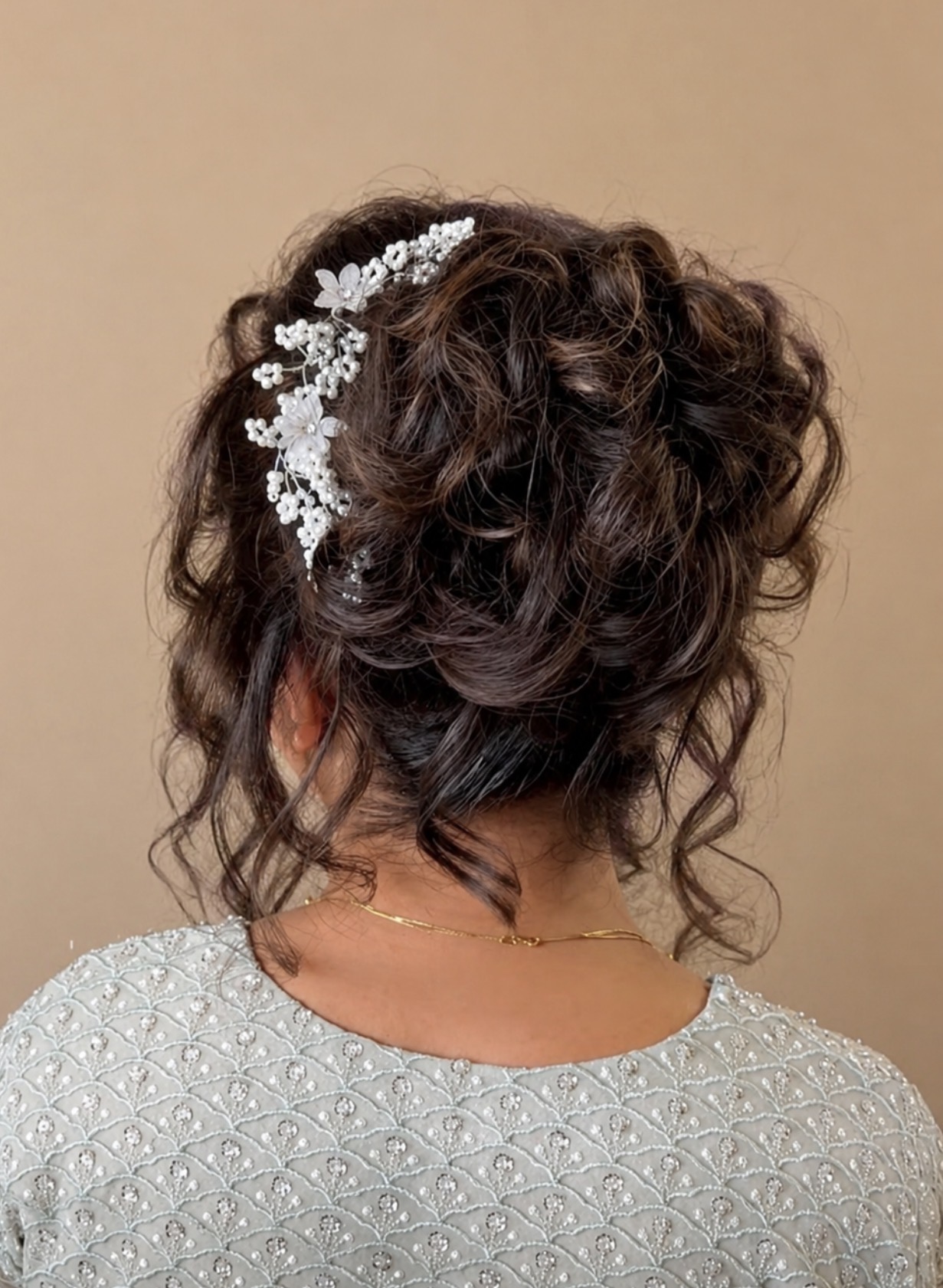 Elegant dark brown updo adorned with a silver floral hair accessory and pinned curls