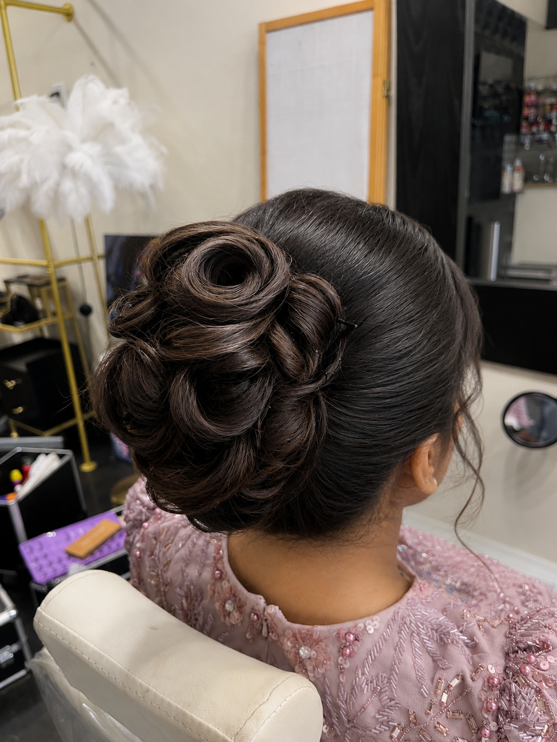 Dark brown hair sculpted into a rose-shaped bun updo for a formal event