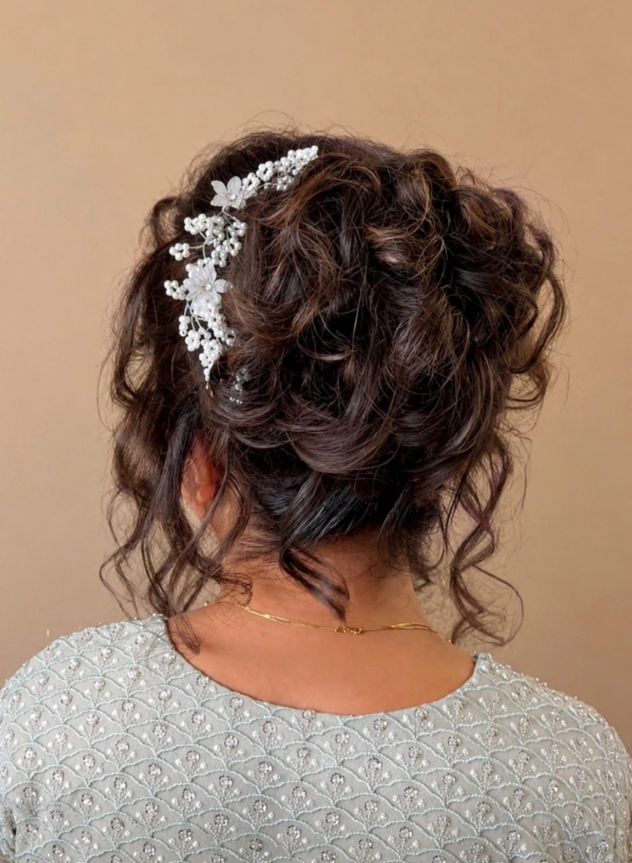 Elegant dark brown updo secured with a pearl and floral hair accessory