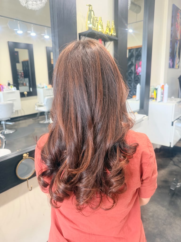 Layered brunette hair with reddish-copper tones styled in soft curls