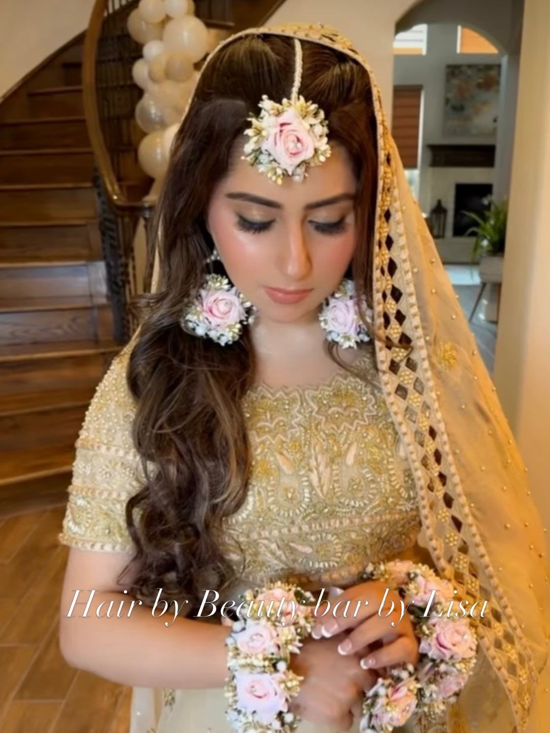 Bridal half-up style with a floral hair accessory and gold embroidered veil