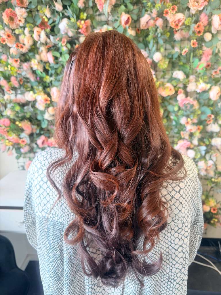 Long auburn-brown hair styled half-up in loose waves
