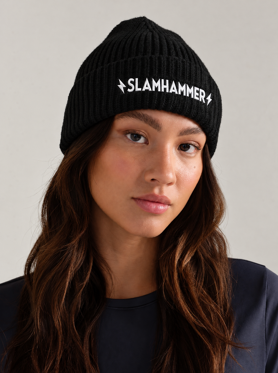 Model in a black beanie embroidered with the Slamhammer logo