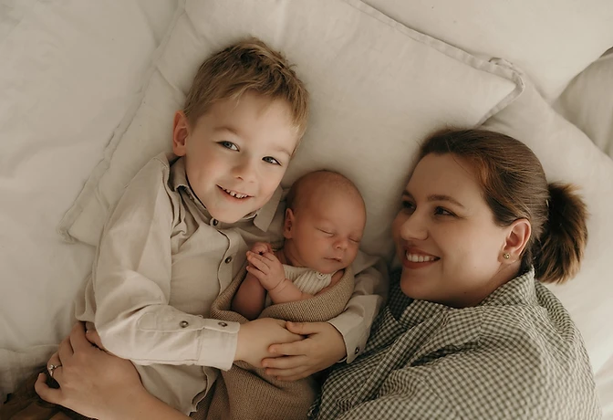 A mother with her children resting together on soft white bedding