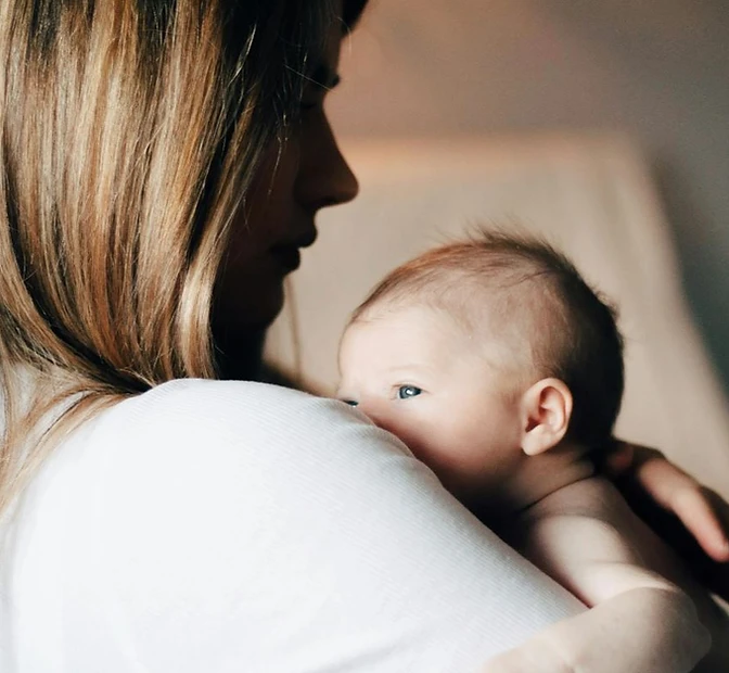 A mother holding her baby over her shoulder