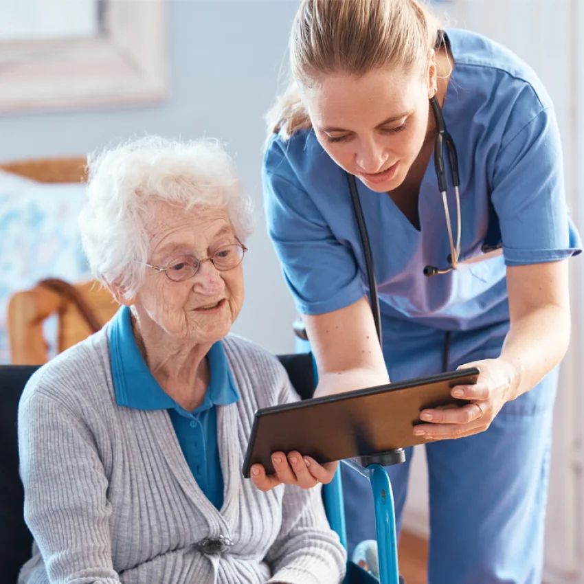 A nurse walking a patient through home dialysis education on a tablet
