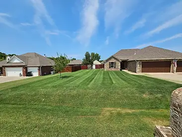 Backyard with mature leafy trees, manicured lawn and garden beds at a Tulsa area Oklahoma home — Thomas Lawn and Landscape lawn care