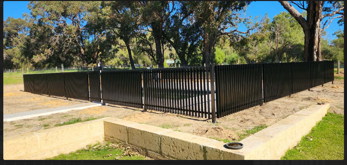 Black vertical aluminium slat perimeter fencing installed around a residential property