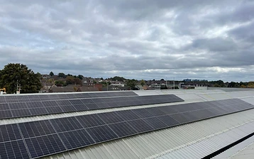 Aerial view of a completed commercial solar installation in long rows on a metal roof