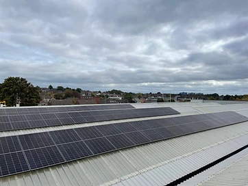 Aerial view of a completed commercial solar panel installation arranged in long rows on a corrugated metal roof