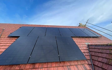 Banks of black solar panels fitted to a light-grey corrugated metal commercial roof