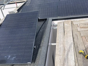 High-angle view of a residential solar panel installation in progress on a flat roof with scaffolding and a power drill on the wooden platform
