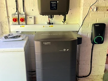 Solarwatt battery, inverter and wall-mounted EV charger installed together on a painted brick wall