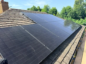 Rooftop solar array fitted to mossy clay tiles with a mesh critter guard and a brick chimney stack