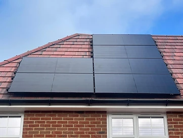 Completed residential solar panel installation on a red-tiled roof, featuring two arrays of all-black solar modules on a brick property