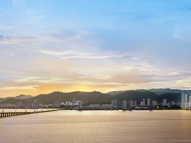 The LightHauz Penang by EXSIM — 57-storey freehold waterfront luxury tower glowing at sunset beside the Penang Bridge