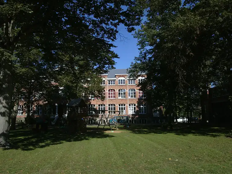 Bakstenen gebouw met speeltuin en oude bomen in Rotselaar, herkenningspunt voor een EPC-keuring in Rotselaar