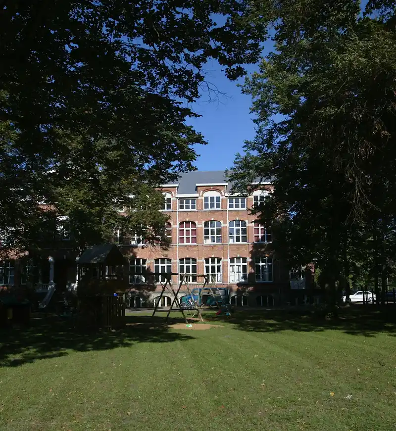 Bakstenen gebouw met speeltuin en oude bomen in Rotselaar, herkenningspunt voor een EPC-keuring in Rotselaar