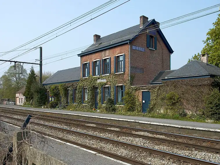 Treinstation van Oud-Heverlee met bakstenen gebouw en blauw naambord, herkenningspunt voor een EPC-keuring in Oud-Heverlee