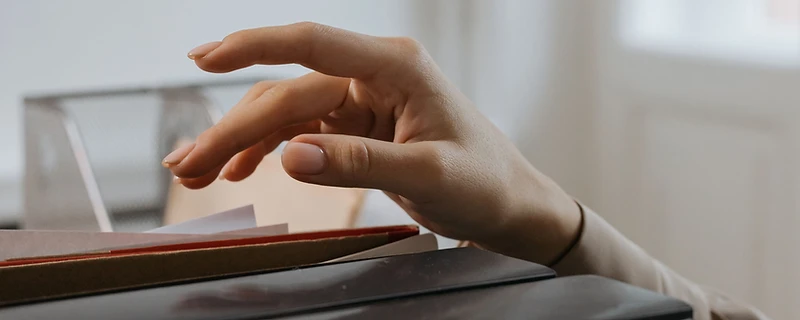 Hand die een stapel bouwdossiers en documenten raakt, klaar om de aanstiplijst voor een EPC-keuring in Leuven af te werken