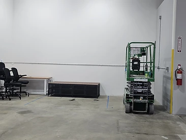 Open commercial work area with concrete floor, storage bench, and a scissor lift