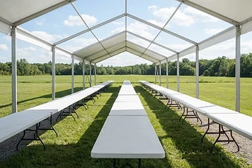 Large white event tent glowing at dusk in a green meadow