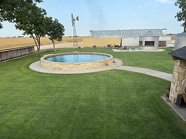 Vibrant green Palisades Zoysia lawn around a stone pool surround