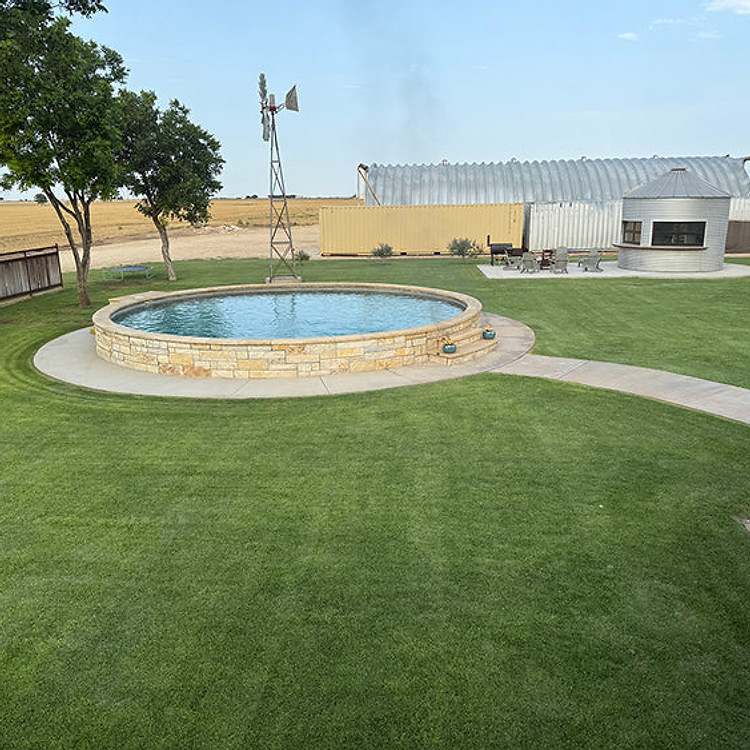 Vibrant green Palisades Zoysia lawn around a stone pool surround