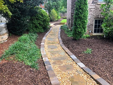 Curving flagstone walkway with river pebbles and a brick edge