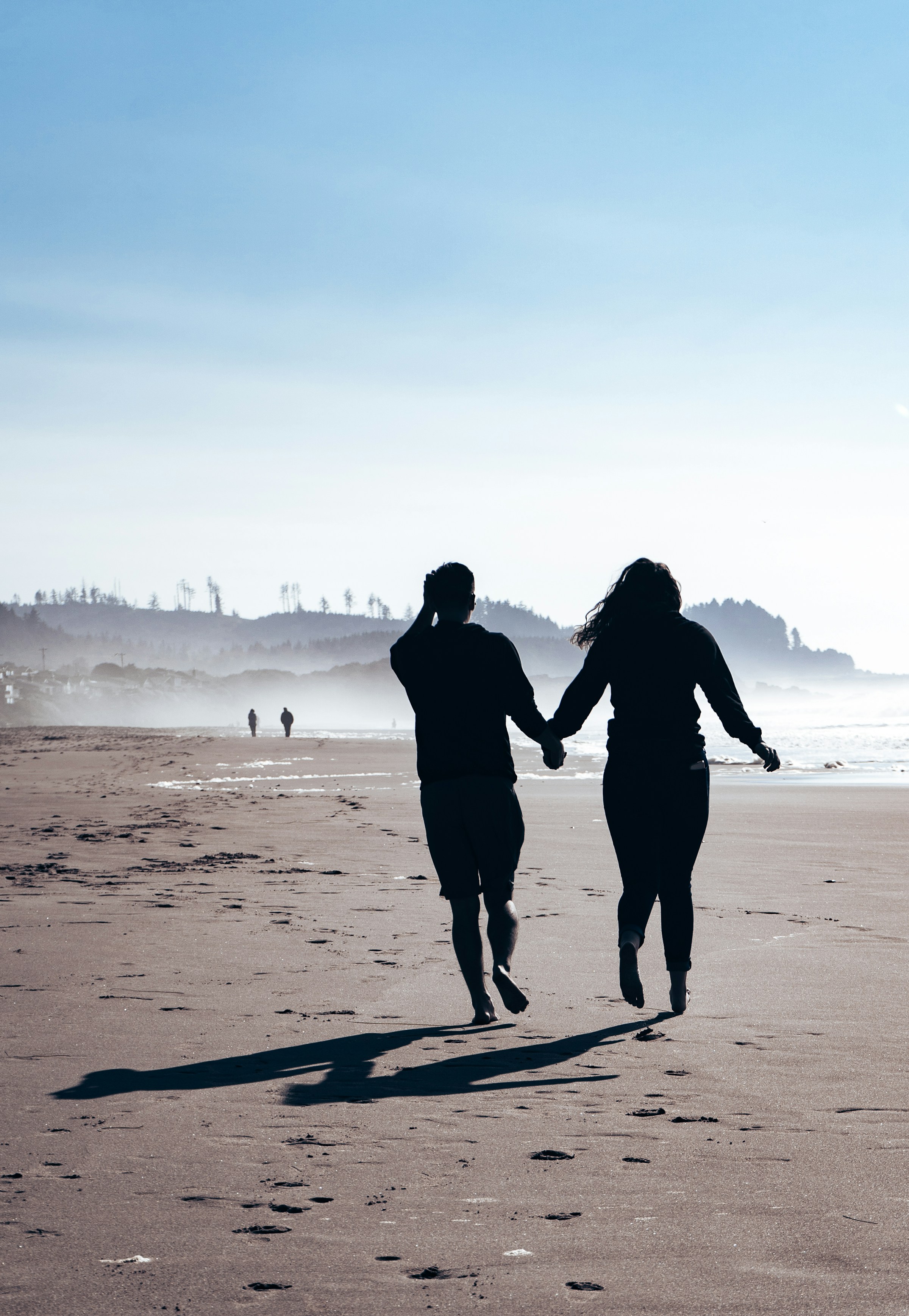A couple walking hand-in-hand along the beach at dawn
