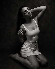 Black and white portrait of a woman kneeling against a dark backdrop