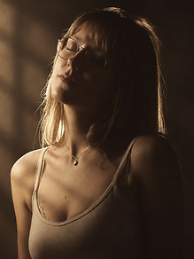 Linn-Kristin E. with her eyes closed in warm directional light, striped shadows falling behind her
