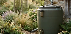 A close-up of a rain barrel with a fine mesh screen securely fastened over the intake to keep debris and insects out.