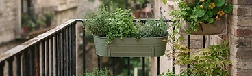 A modern balcony featuring a metal railing equipped with several colorful rectangular planters filled with vibrant flowers and trailing herbs.