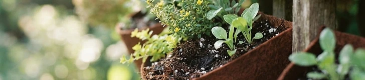 A close-up shot of hands mixing dark organic potting soil with white perlite inside a large plastic bin.