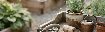 A close-up shot of an elderly gardener's hands wearing gardening gloves, holding a lightweight ergonomic hand trowel with a bright yellow, thick-grip handle.