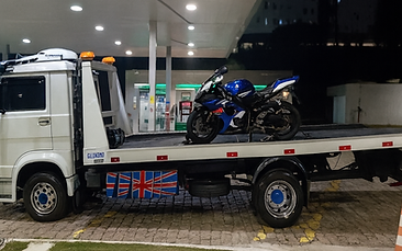 Motocicleta sendo transportada em plataforma de guincho durante atendimento noturno.