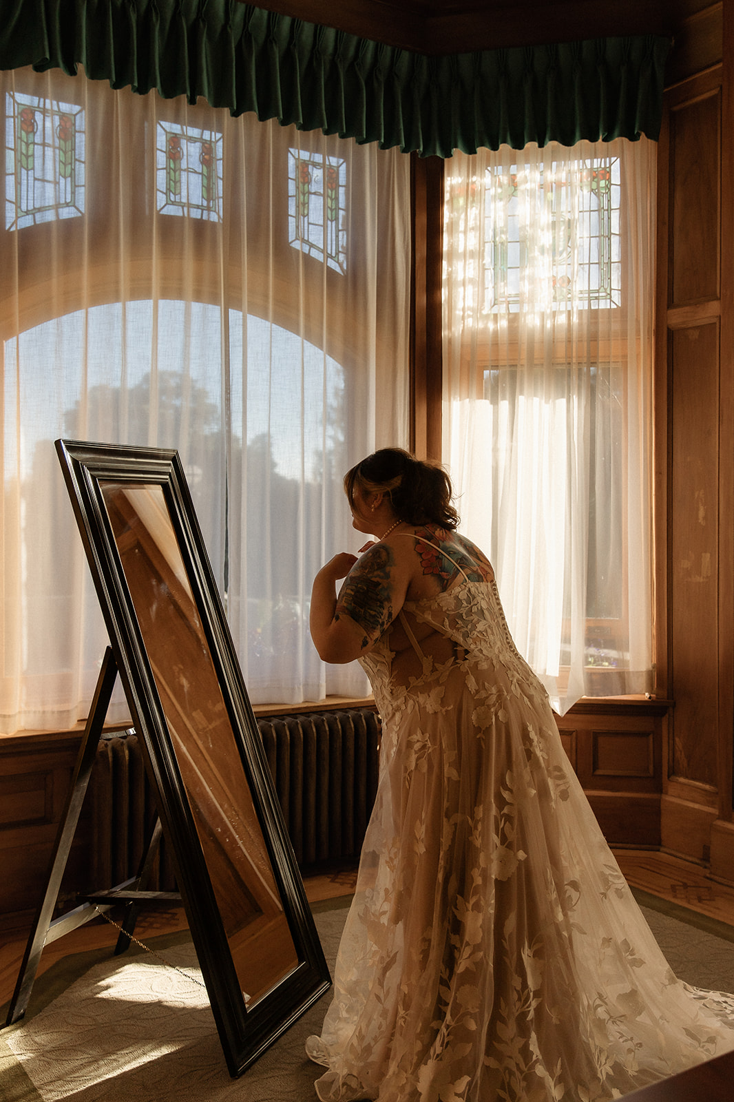 A bride in a lace wedding gown reflected in a floor mirror