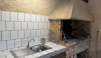 Cuisine d'été avec évier, plan de travail et barbecue en brique