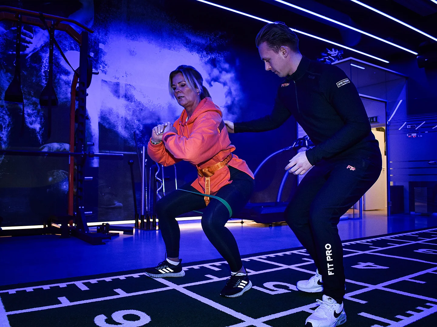 Personal trainer begeleidt een squat met weerstandsband bij FITPRO in Laren