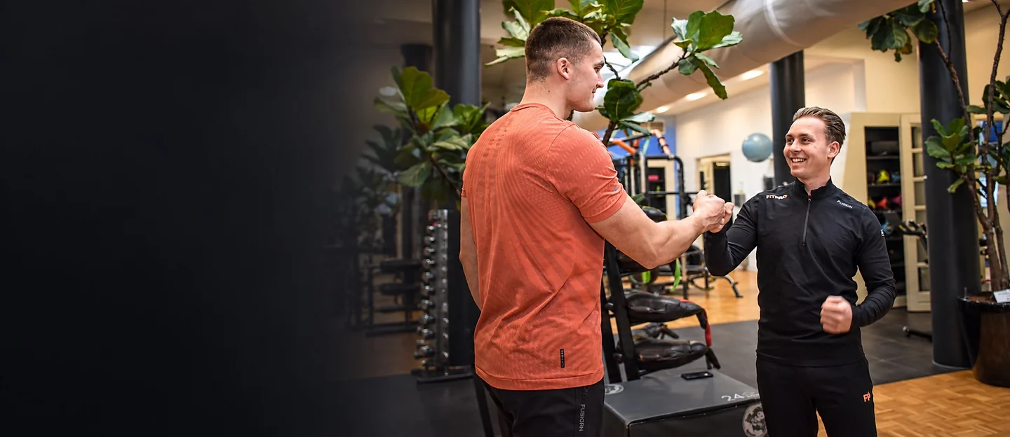 Personal trainer en member geven elkaar een hand in de gym van FITPRO in Laren
