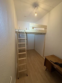 Hochbett in einem schmalen Zimmer, Stufenleiter und Schreibtisch darunter