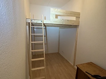 Hochbett in einem schmalen Zimmer, Stufenleiter und Schreibtisch darunter