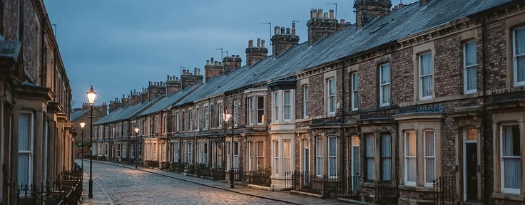 Older terraced street at dusk with bay windows and chimney stacks along the roofline