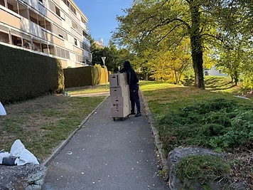 Membre de l'équipe déplaçant une pile de cartons sur un diable le long d'un chemin pavé