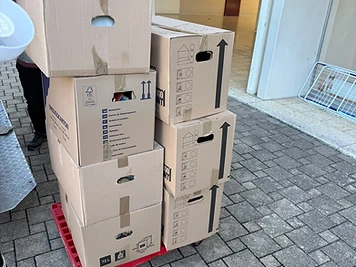 Transpalette rouge chargé de cartons de déménagement devant des piliers