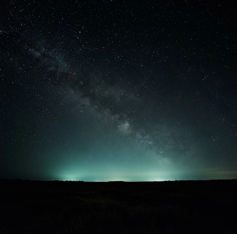 Cielo nocturno despejado sobre Panamá con estrellas y un suave brillo verde en el horizonte