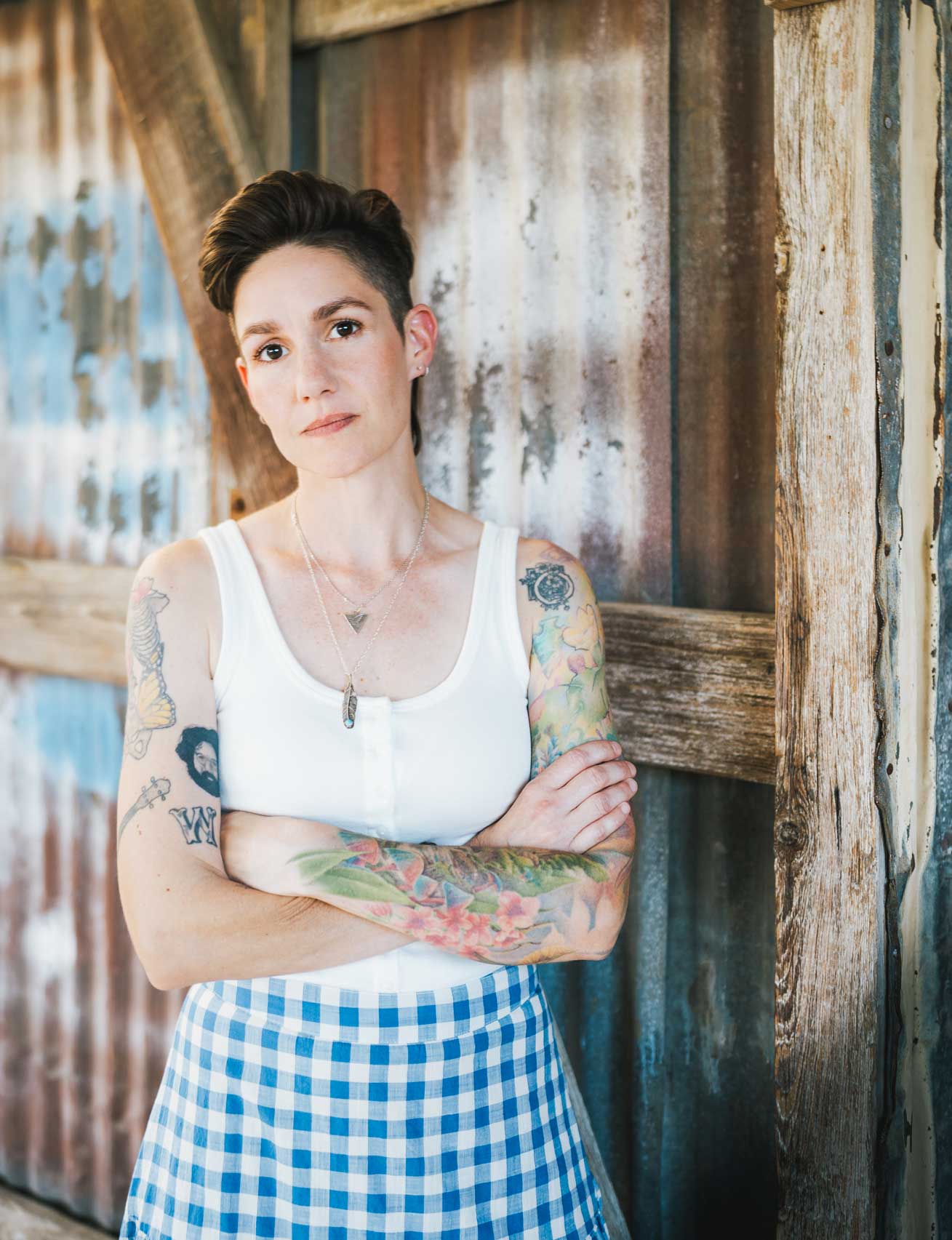 Emily McLoud arms crossed at barn door, serious expression, Austin Americana artist